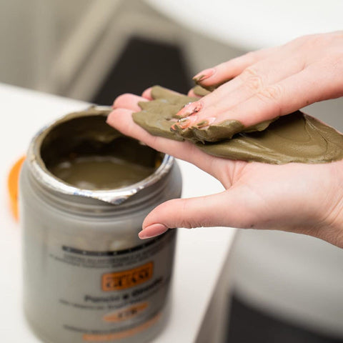 GUAM Algenfango offene Dose mit Meeresalgenfango in der Hand aufgetragen zur Straffung Entwässerung und Cellulite Reduktion. Naturpräparate Dieterich