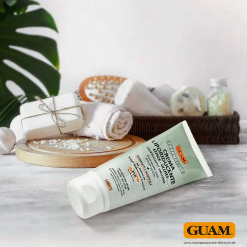 GUAM Tourmaline Liporeduzierende Intensiv Creme Gesäß und Oberschenkel gegen Cellulite mit Meeresalgen und mineralischen Aktivstoffen auf Marmoroberfläche vor Wellness Accessoires wie Handtüchern Seifen Massagebürste und Badesalz im Badezimmer. Naturpräparate Dieterich
