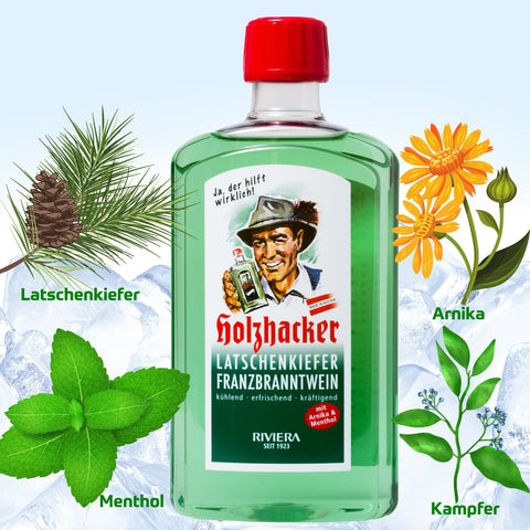 Holzhacker Latschenkiefer Franzbranntwein in 500 ml Flasche mit winterlich-kühler Gebirgskette im Hintergrund und einem Latschenkieferzweig, Arnikablüten, Minzblättern und Kampferzweig. | Naturpräparate Dieterich