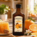 Flasche Riviera Immunkomplex mit Propolis und Honig neben Honigwabe, Honiglöffel und frischen Orangen in heller Küche | Naturpräparate Dieterich